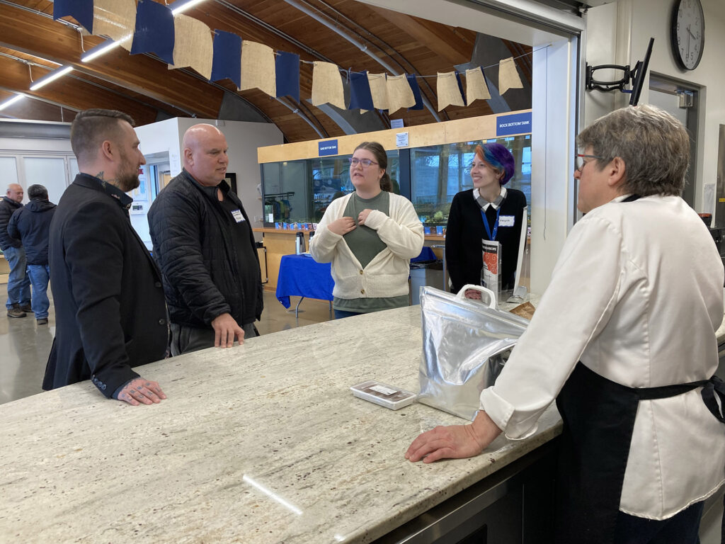 Brady Calancie, a Regional Business Advisor with Community Futures Central Island, speaks with four entrepreneurs during an event.