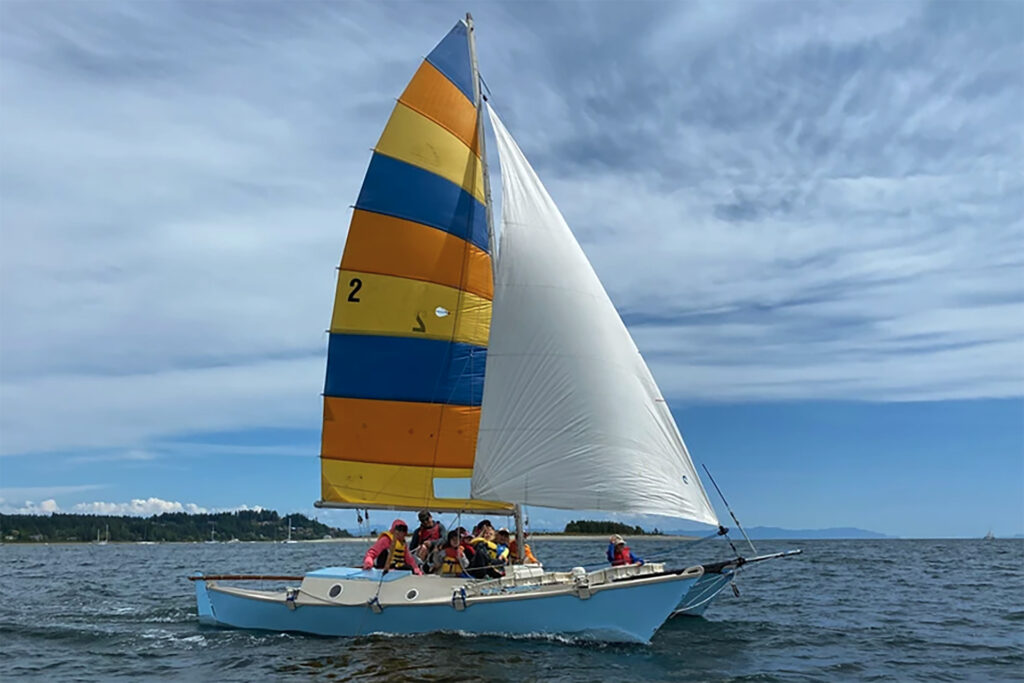A Compass Adventure sailing lesson, with a school group of young kids on a small sailboat in comox harbour.