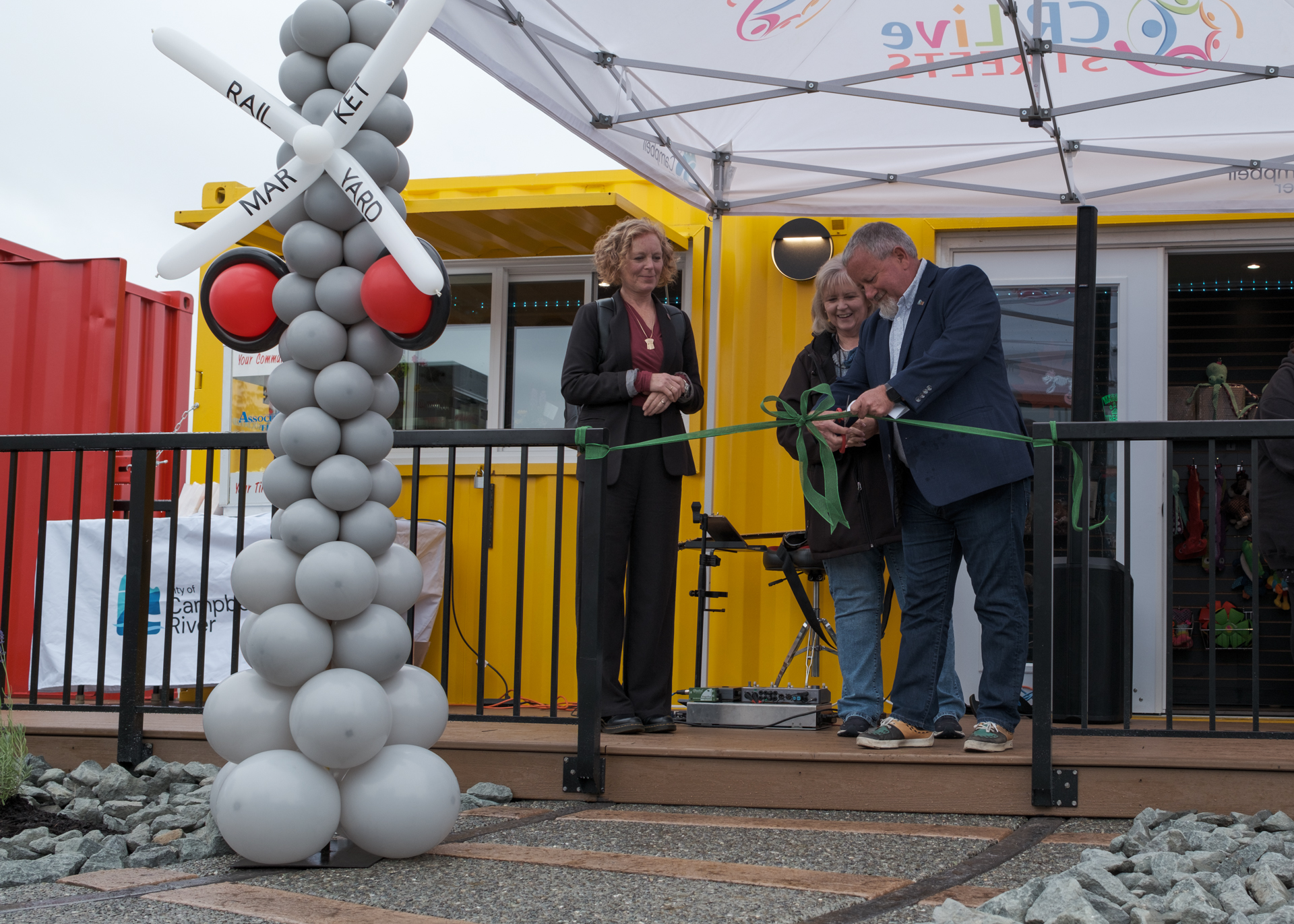 Kermit Dahl, Mayor of Campbell River, cuts the ribbon during the Rail Yard Market grand opening alongside Vickey Brown, Mayor of Cumberland and Director of Island Coastal Economic Trust, and Michele Babchuk, former MLA for North Island.